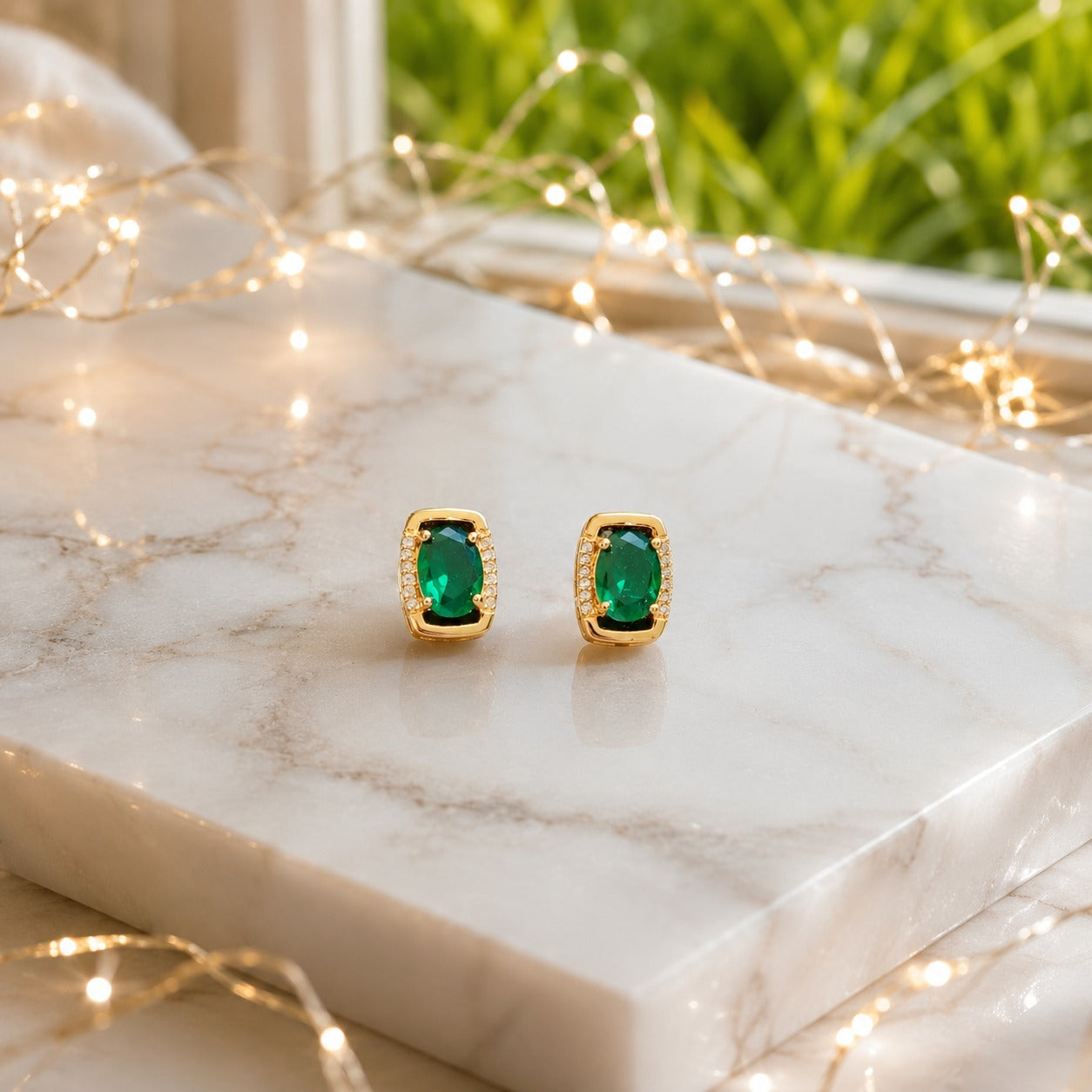 Oval gemstone stud earrings displayed on a polished marble slab with luxury lifestyle décor, highlighting the gemstone brilliance and premium gold or silver finish.