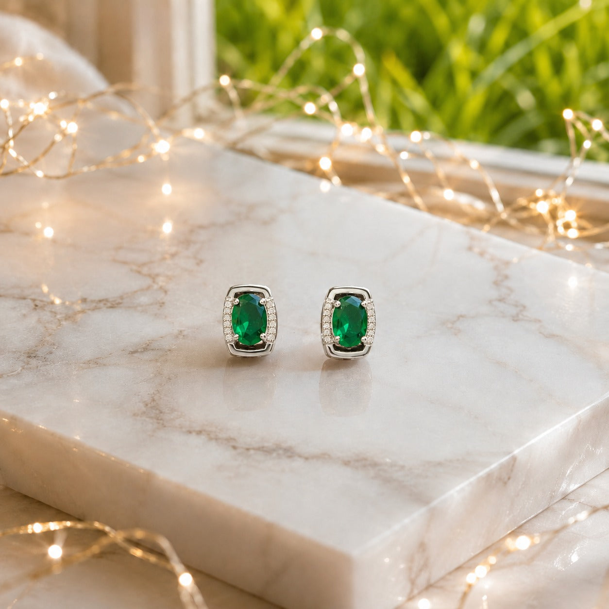 Oval gemstone stud earrings displayed on a polished marble slab with luxury lifestyle décor, highlighting the gemstone brilliance and premium gold or silver finish.