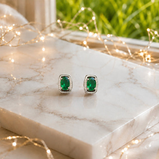 Oval gemstone stud earrings displayed on a polished marble slab with luxury lifestyle décor, highlighting the gemstone brilliance and premium gold or silver finish.