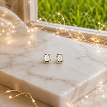 Oval gemstone stud earrings displayed on a polished marble slab with luxury lifestyle décor, highlighting the gemstone brilliance and premium gold or silver finish.