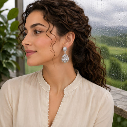 Woman wearing premium silver teardrop crystal drop earrings with pear-cut centre stone and sparkling pavé detailing, photographed in soft natural light for luxury jewellery styling.