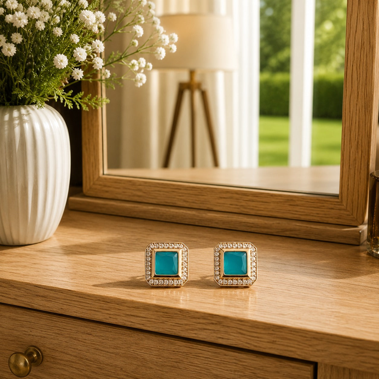 Premium square halo turquoise crystal stud earrings with princess-cut centre stone displayed on a polished wooden dressing table in a luxury lifestyle setting with floral décor and natural daylight.