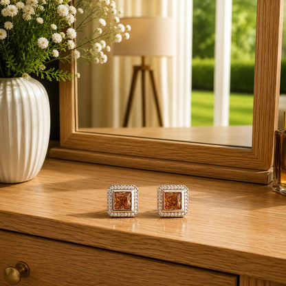 Premium square halo  champagne crystal stud earrings with princess-cut centre stone displayed on a polished wooden dressing table in a luxury lifestyle setting with floral décor and natural daylight.