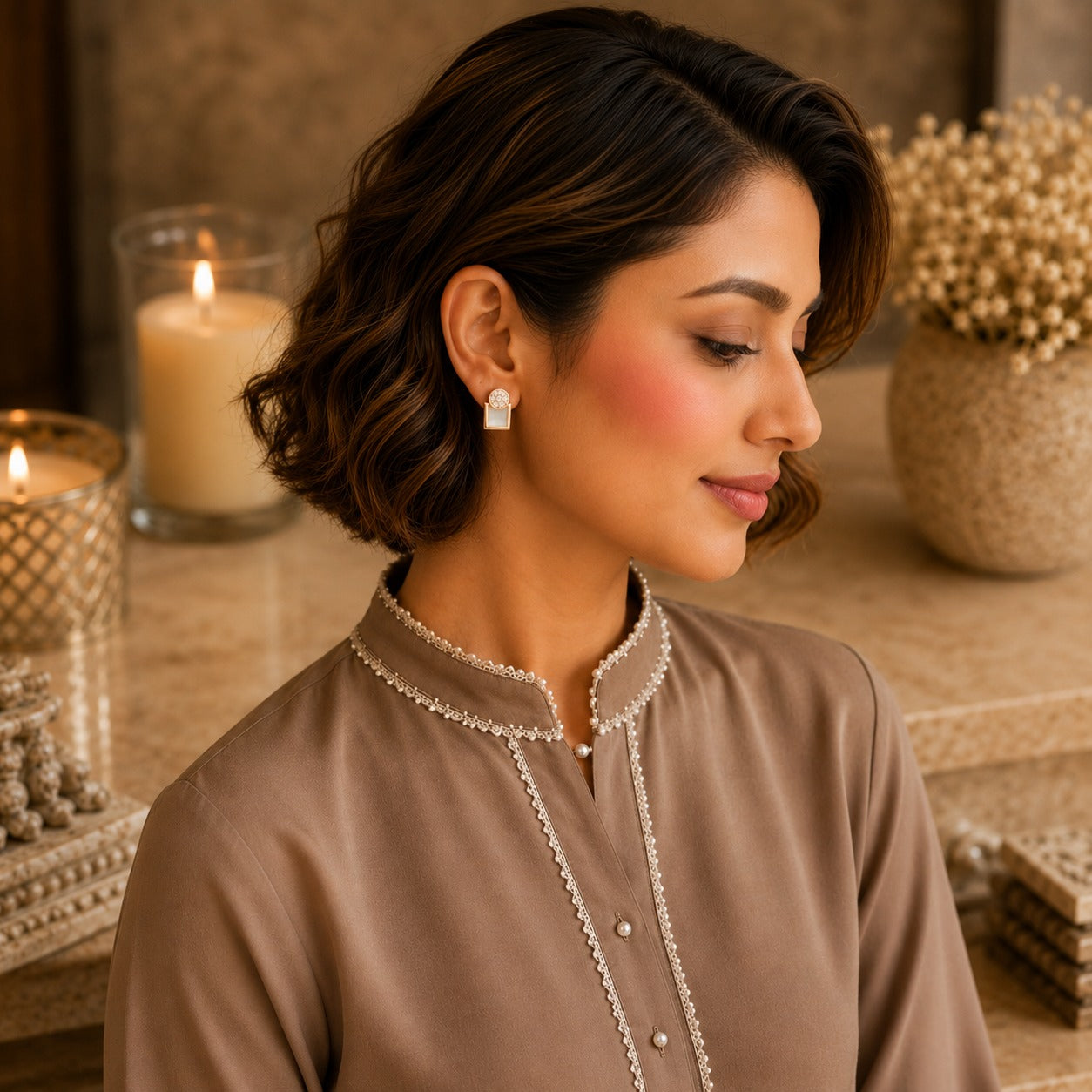 Woman wearing gold geometric mother of pearl zircon stud earrings with a taupe embroidered kurta in a luxury indoor setting, showcasing modern everyday jewellery.
