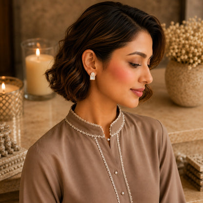 Woman wearing gold geometric mother of pearl zircon stud earrings with a taupe embroidered kurta in a luxury indoor setting, showcasing modern everyday jewellery.