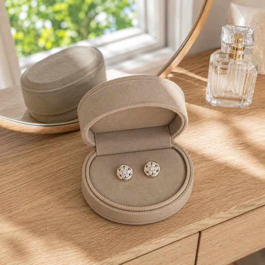 Gold floral crystal stud earrings displayed in a premium beige velvet jewellery box on a light oak dressing table
