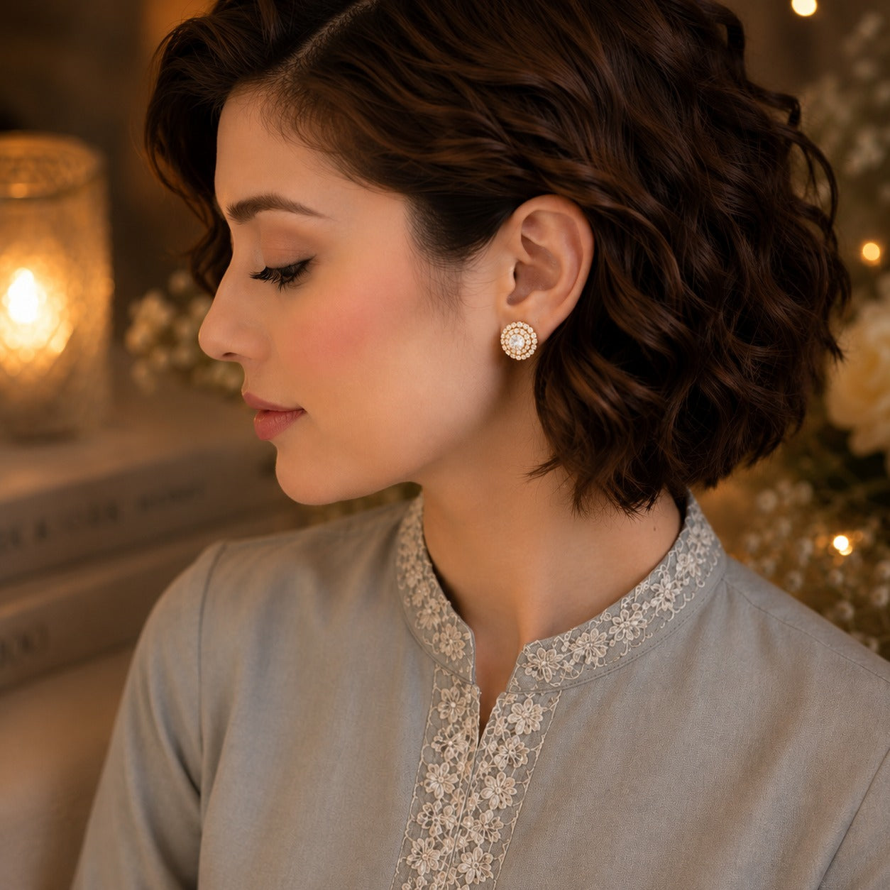 Woman wearing elegant round halo crystal stud earrings with a gold-tone finish and brilliant center stone in a soft luxury portrait.