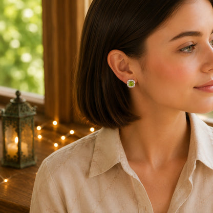 Woman wearing halo cushion-cut crystal stud earrings with a lime green,  stone in a warm natural daylight setting