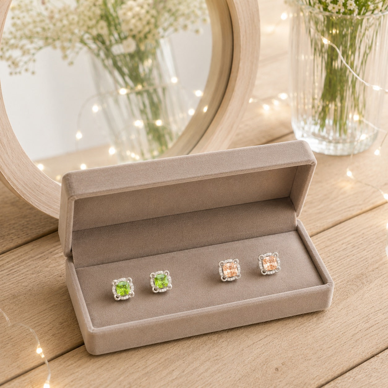 Peridot green and champagne crystal square halo stud earrings displayed in a premium velvet jewellery box with a soft mirror backdrop.