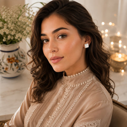 Woman wearing square mother of pearl stud earrings with a soft neutral outfit, showcasing minimalist everyday jewellery.