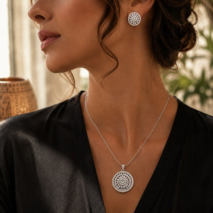 Model wearing a silver floral pendant necklace and matching stud earrings with mint green centre stones in a close-up lifestyle portrait.