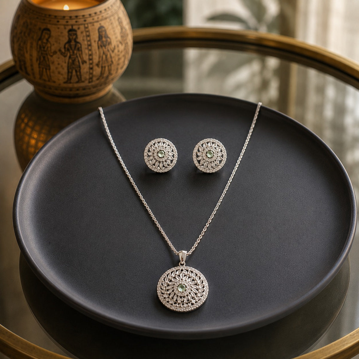 Silver floral pendant and matching stud earrings jewellery set with mint green centre stones displayed on a premium charcoal ceramic plate in a luxury lifestyle setting.