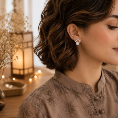 Model wearing elegant silver geometric crystal drop earrings featuring baguette-cut crystals and round brilliant stone drops in a luxury lifestyle setting.