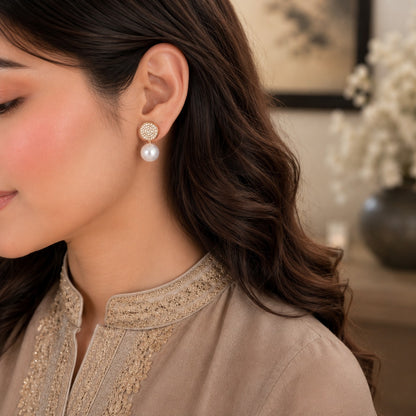 Model wearing elegant gold pavé pearl drop earrings with sparkling crystal tops and luminous white pearl drops in a refined luxury setting.