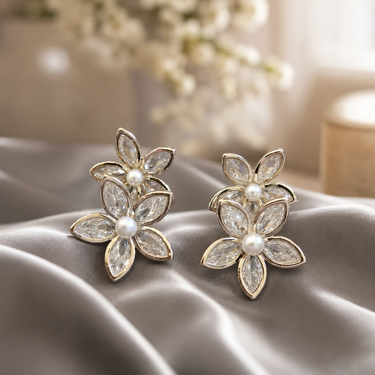 Silver floral crystal pearl earrings featuring layered marquise-cut crystal petals with luminous pearl centers displayed on luxurious satin fabric.