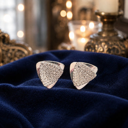 Silver geometric triangular stud earrings with pavé-set crystals displayed on luxurious navy blue velvet fabric in a premium jewellery presentation.