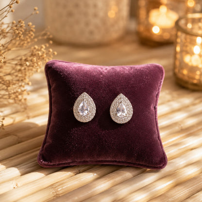 Silver teardrop stud earrings with a clear pear-cut centre stone surrounded by a sparkling pavé halo and butterfly stopper back
