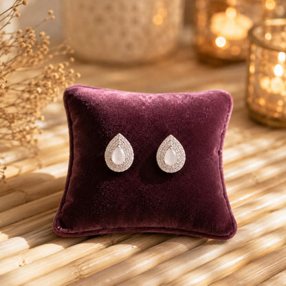 Silver teardrop stud earrings with a pearlescent white pear-cut centre stone surrounded by a sparkling pavé halo and butterfly stopper back