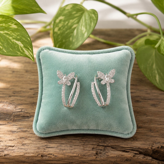 Silver floral stud earrings with pavé stones, open curved frame design, and butterfly stopper back