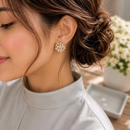 Model wearing gold floral crystal stud earrings with textured leaf details in a soft side-profile portrait.