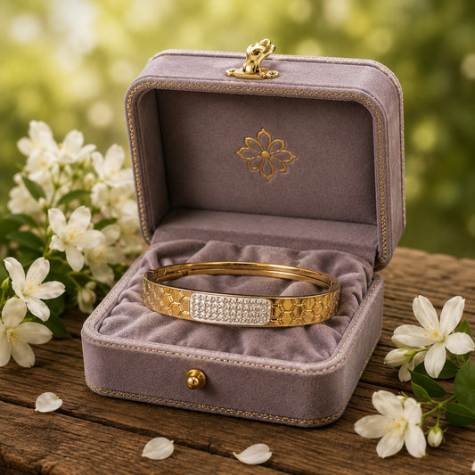 Gold geometric crystal cuff bracelet displayed inside a premium mauve velvet jewellery box surrounded by white flowers
