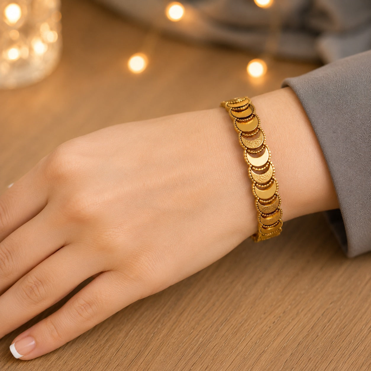 Gold crescent link bracelet worn on the wrist on a natural wood surface