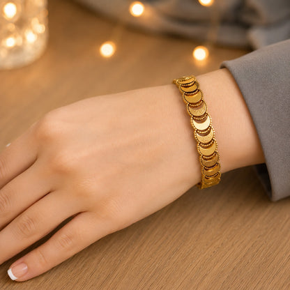 Gold crescent link bracelet worn on the wrist on a natural wood surface