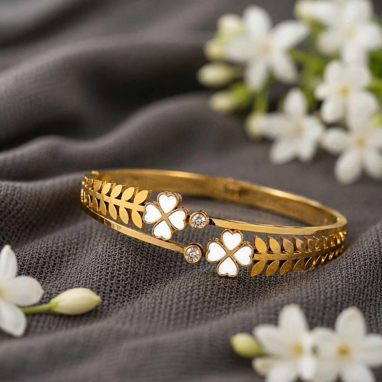 White clover front-open magnetic bracelet on charcoal grey fabric with jasmine flowers.
