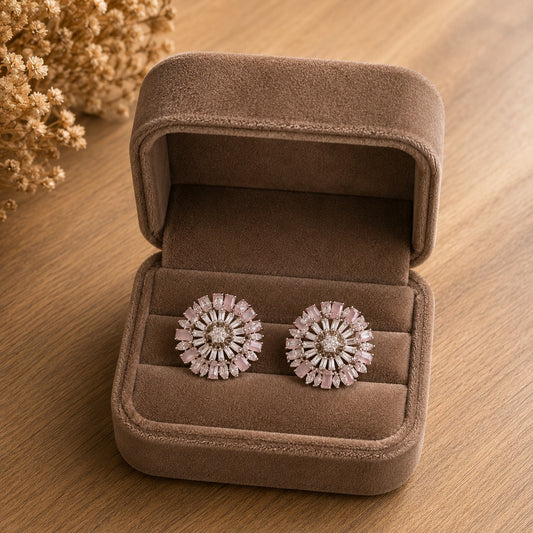 Rosé floral stud earrings displayed inside a premium taupe velvet jewelry box on a wooden tabletop with dried florals.