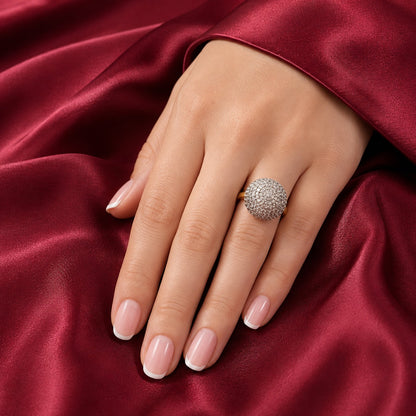 Pavé dome statement ring worn on a hand with French manicured nails against rich burgundy satin fabric.