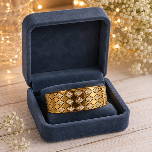 Gold-tone lattice cuff bracelet with crystal detailing and closed locking clasp presented in a navy velvet jewelry box.