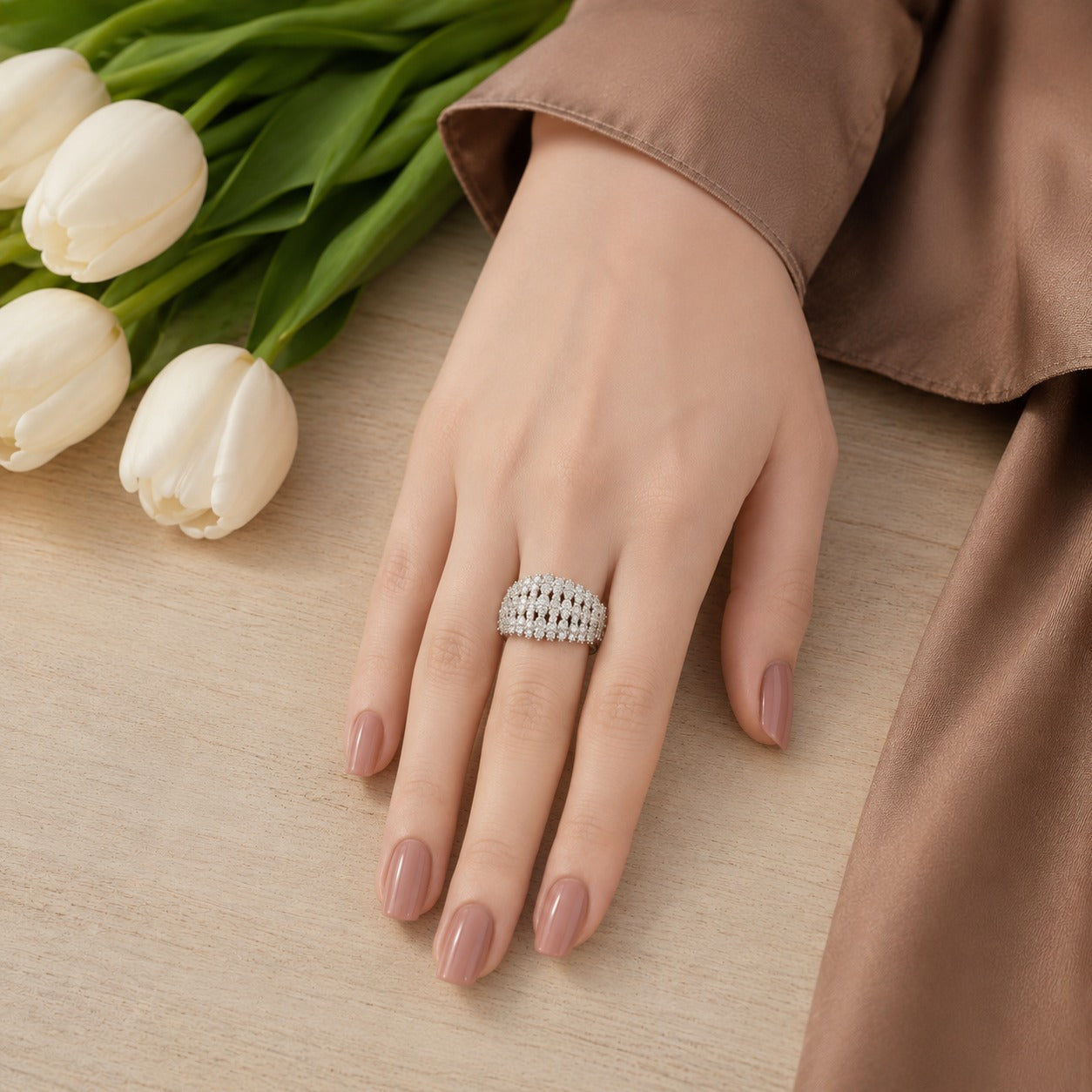 S925 sterling silver multi-row crystal statement ring worn on a hand with a neutral manicure against a soft wooden background.