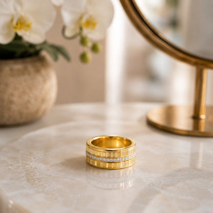 Close-up of a gold-tone stainless steel textured band featuring a sparkling crystal center line on a polished marble surface.
