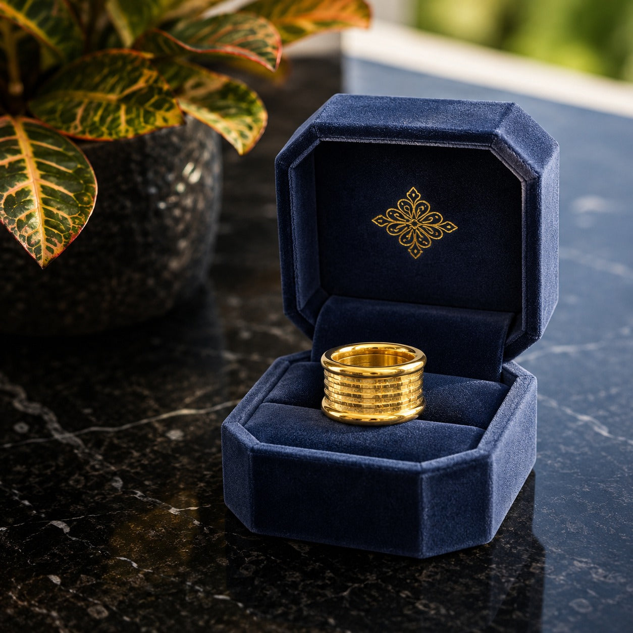 Gold-tone stainless steel statement band ring displayed inside a premium navy velvet jewellery box.