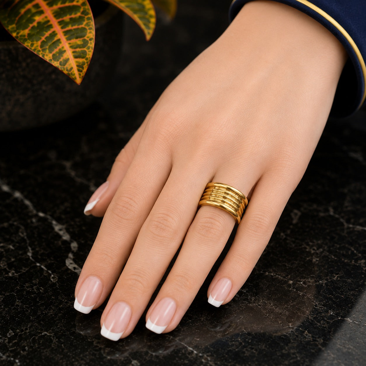 Close-up of a solid wide stainless steel gold ring with a polished finish on a luxury marble background.