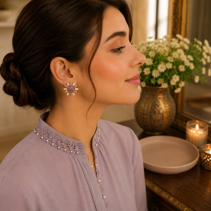 Female model wearing lavender floral crystal stud earrings in a side-profile portrait highlighting the detailed floral design