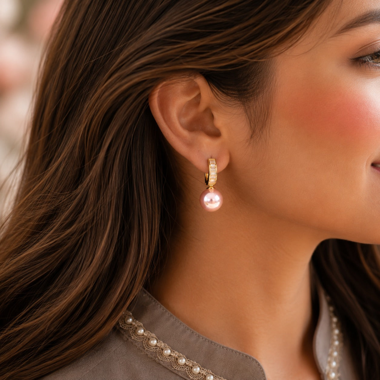 Close-up of a model wearing Blush Pink pearl drop hoop earrings with baguette crystal detailing.