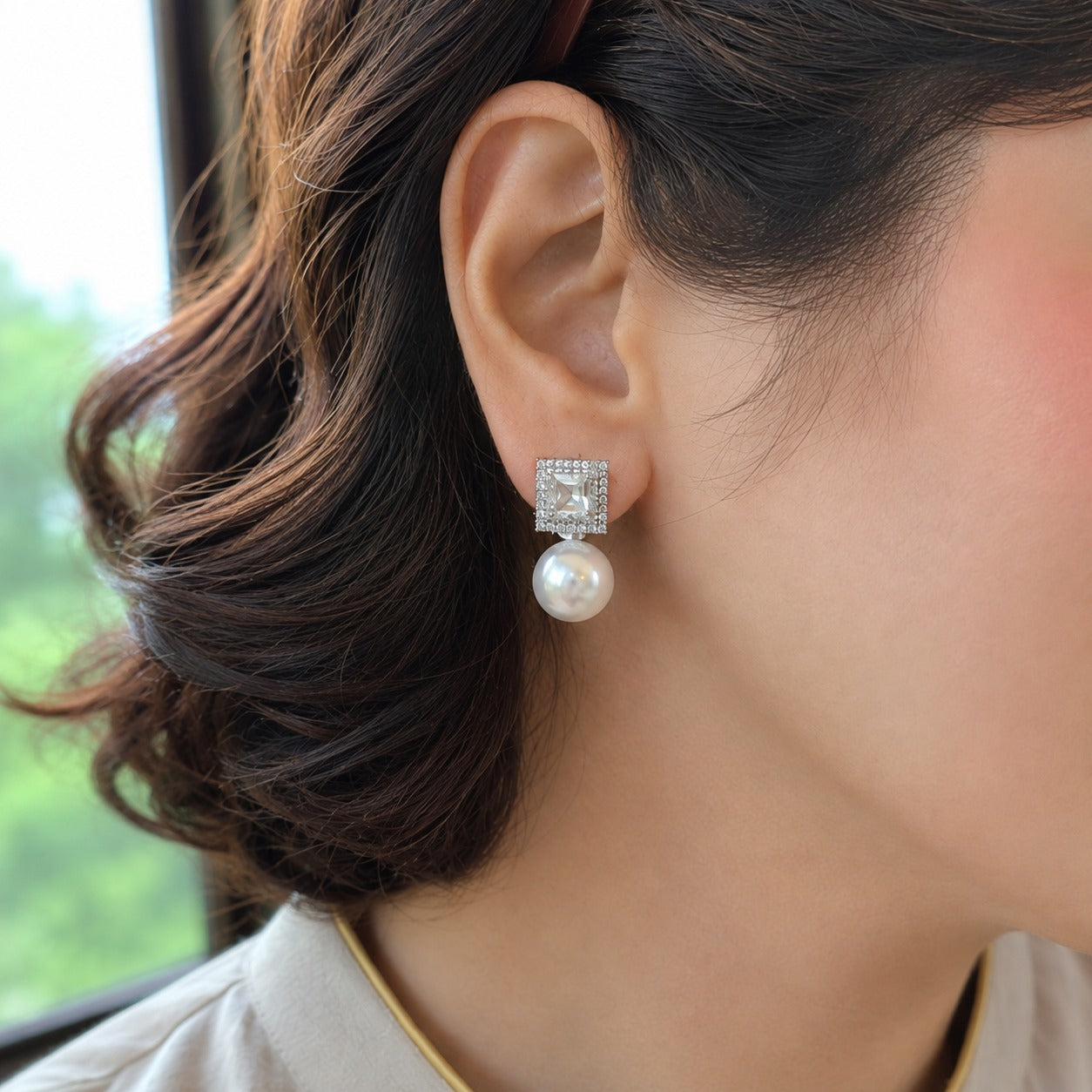 Close-up of silver geometric zircon stud earrings with round white pearl drops