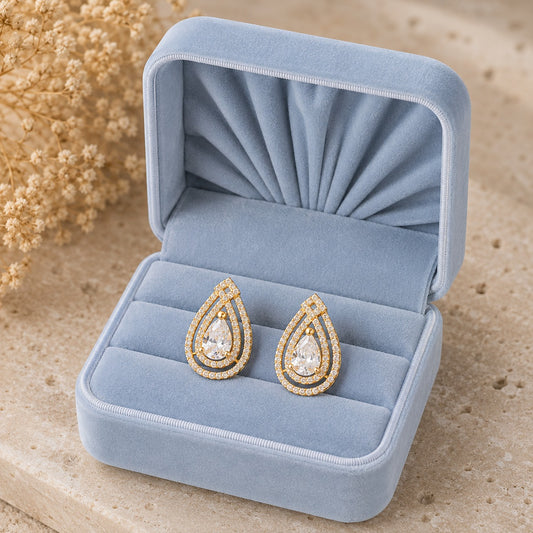 Gold pear-cut zircon teardrop stud earrings displayed in soft blue velvet jewellery box
