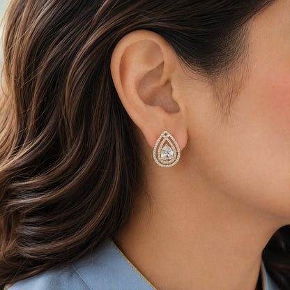 Close-up of gold teardrop zircon stud earring with pear-cut centre stone worn on ear