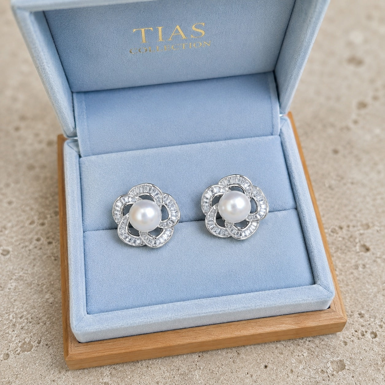 Pearl Loop Stud Earrings in silver with pearl centre and clear stones displayed in blue jewellery bo