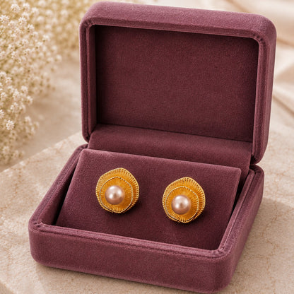 Gold-tone sculptural stud earrings with layered ripple design and luminous pearl centre