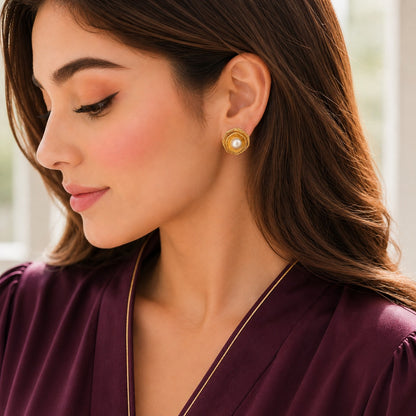 Model wearing gold pearl statement studs with textured circular detailing