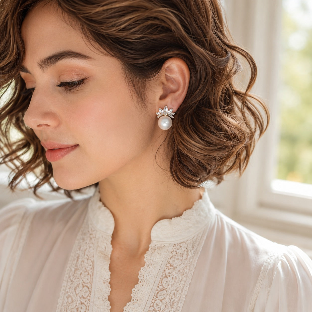 Model wearing statement pearl and crystal stud earrings with a soft neutral outfit
