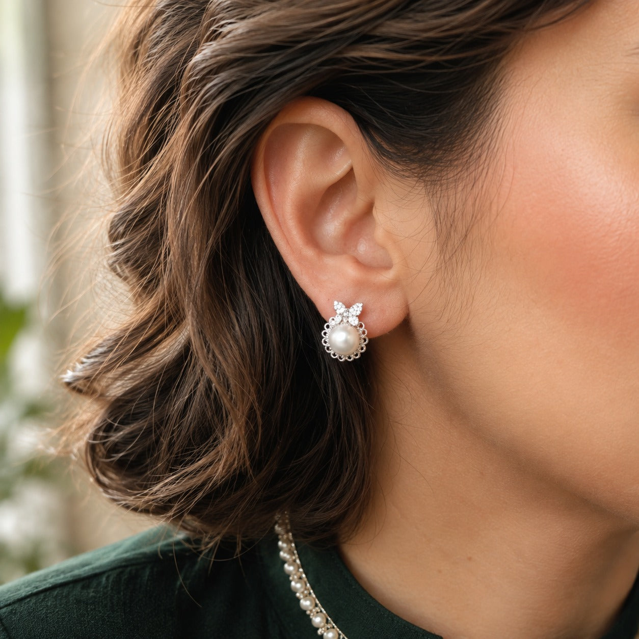 Model wearing butterfly pearl stud earrings with sparkling crystal wing