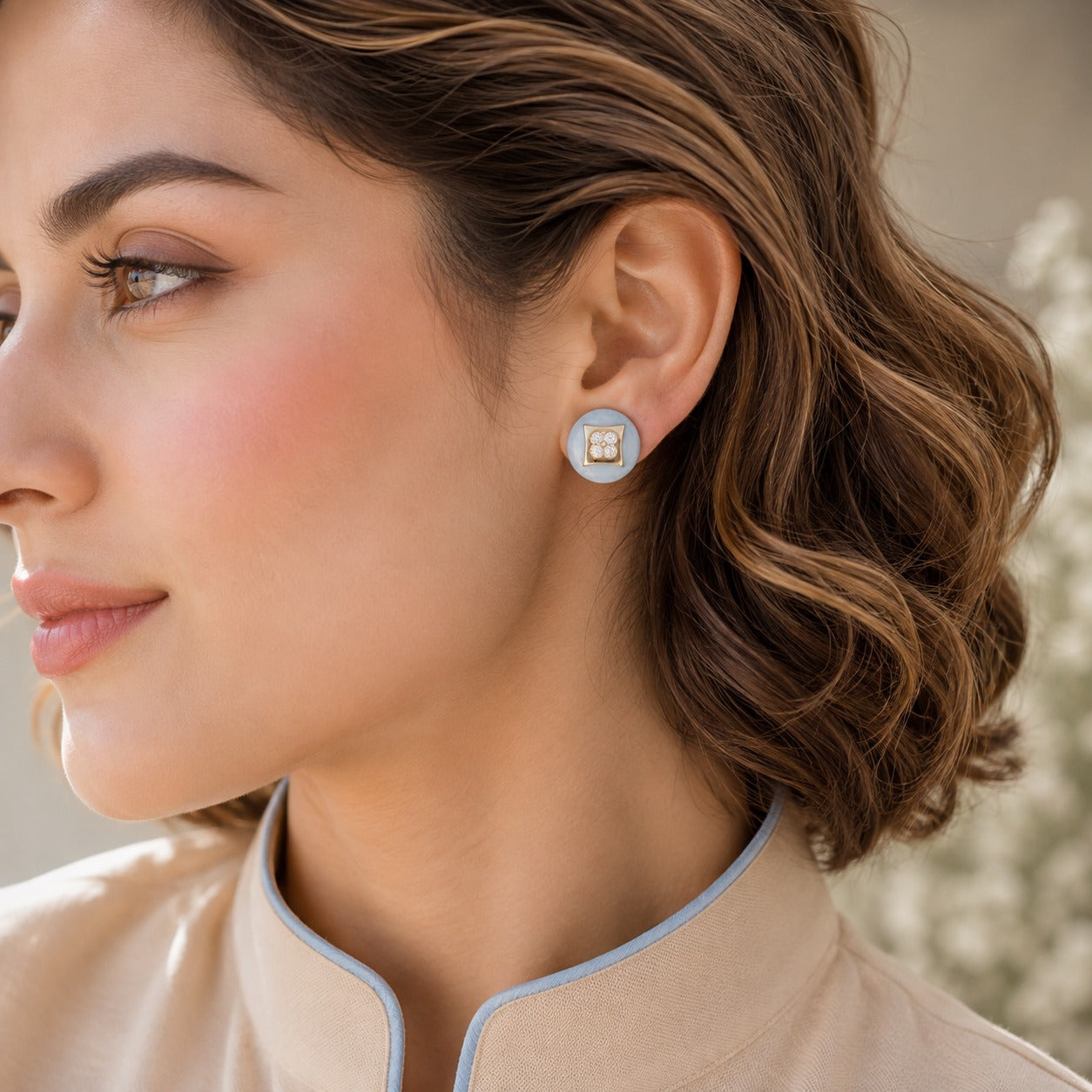 Model wearing Powder Crest Studs featuring powder-blue round bases, gold-tone square centres and four-petal clear zircon detailing.