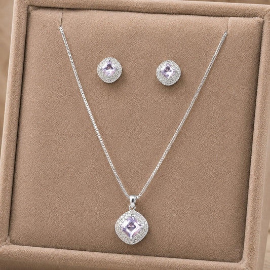 Complete Set: Clear zircon cushion pendant necklace with matching halo stud earrings displayed on a neutral jewellery stand.