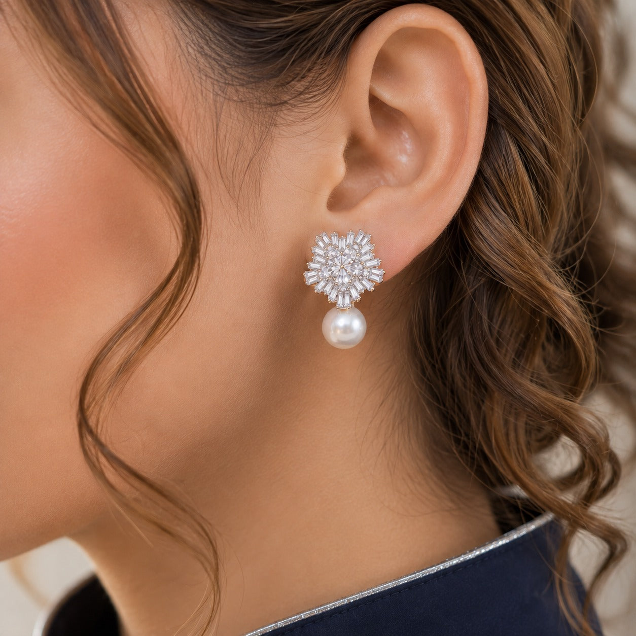 Close-up of clear zircon floral cluster earrings with luminous pearl drops worn on the ear.