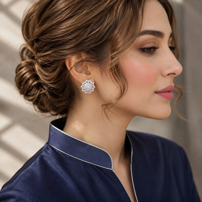 Side-profile model wearing Astra Crest clear zircon stud earrings with a navy formal outfit and swept-back hair.