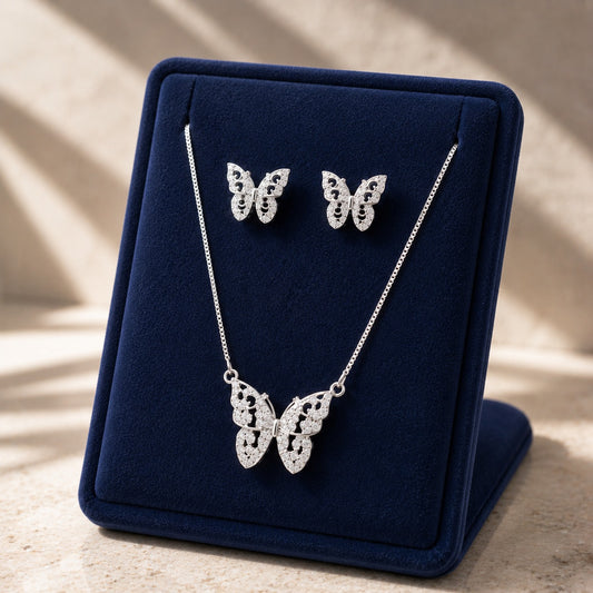 Model wearing a silver butterfly necklace and matching butterfly stud earrings with intricate openwork and clear stone detailing.
